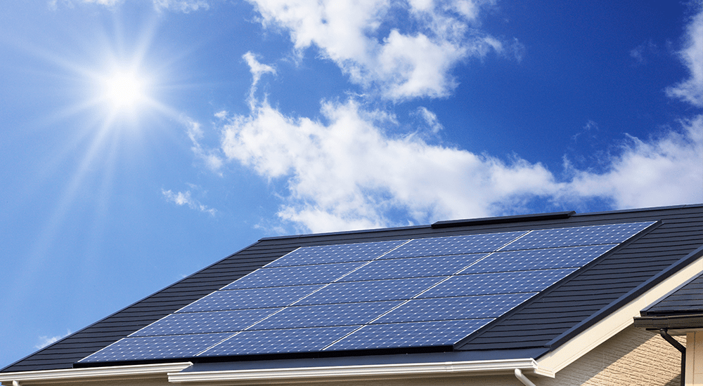 青空の下、瓦屋根に太陽光パネルが設置された住宅